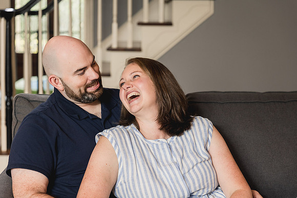 husband and wife laughing together on a couch of their home
