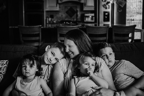 mother snuggles and laughs with her four children on the couch