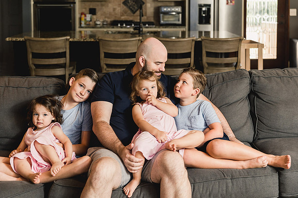 dad snuggles with his 4 kids on the couch during a family photo session