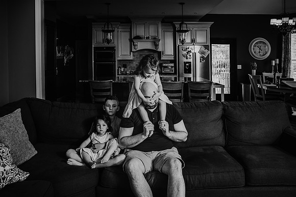 funny image of a father with his daughter on his shoulder while she covers his eyes