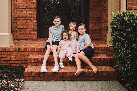 four siblings sitting on the steps of their home for a portrait by monica carlson photography