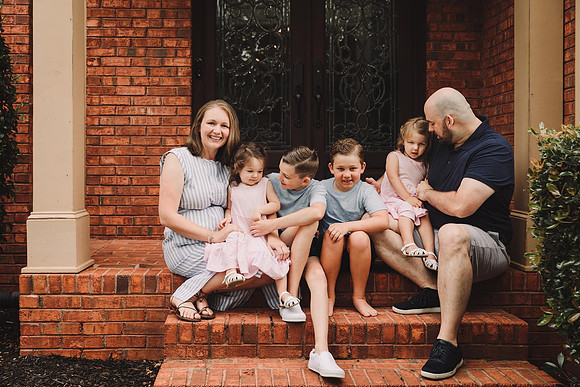 family happily sitting on their front porch during a family lifestyle photo session