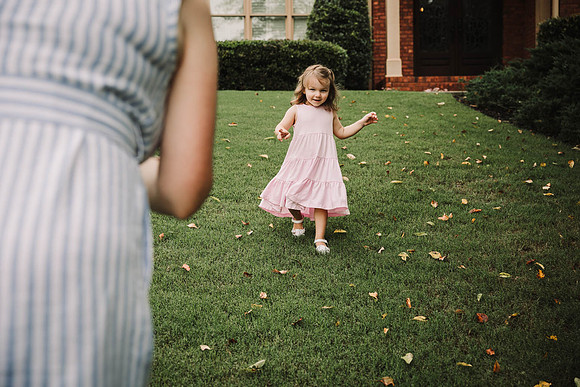little girl runs to her mother outside their home