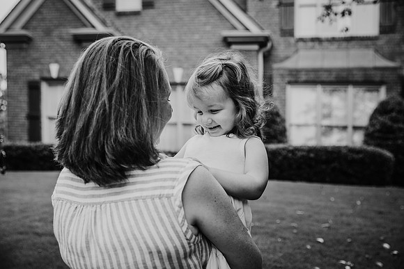 little girl happily looks at her mother while being carried