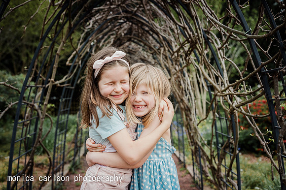 two girls happily hugging in a garden tunnel