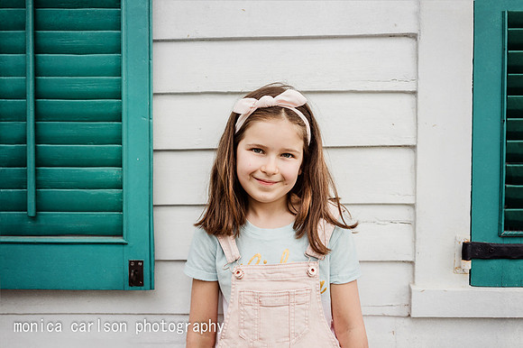 little girl standing between turquoise shutters in Roswell