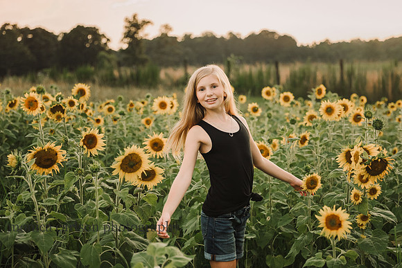 strawberry blonde girl spins on a field of sunflowers