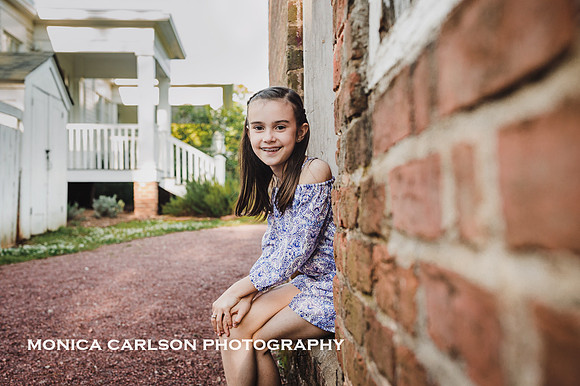 Tween girl sitting in a in a brick building during a family photo session in Roswell, GA