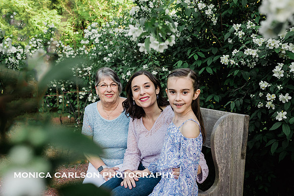 three generations of women sitting in a garden during a family photo session