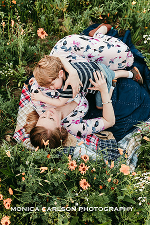 woman and son lay in a field of flower during a maternity session with monica carlson photography