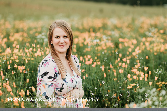 portrait of a pregnant woman sitting in a field of flowers