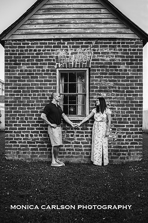 man and wife holding hand in front of a brick building by monica carlson