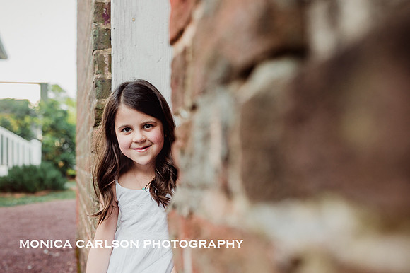 happy little girl sitting in the frame of a brick house