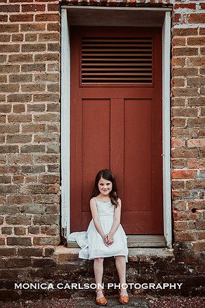 little girl sits in front of a red door at Barrington hall