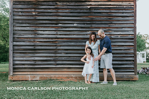 family of three portrait in front of a wooden structure on the Barrington Hall property by monica carlson photography
