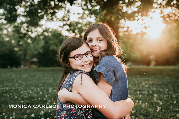 sisters hugging at sunset during a family photo session