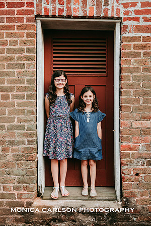 sisters standing in the door frame of a brick building at a historic home in Roswell, GA