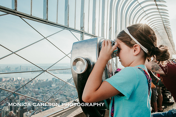 girl looking through binoculars on the observation deck of the empire state