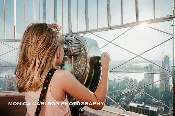 girl looking through the binoculars on the empire state building at sunset