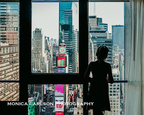 girl looking out a window of the Marriott Marquis over TImes Square