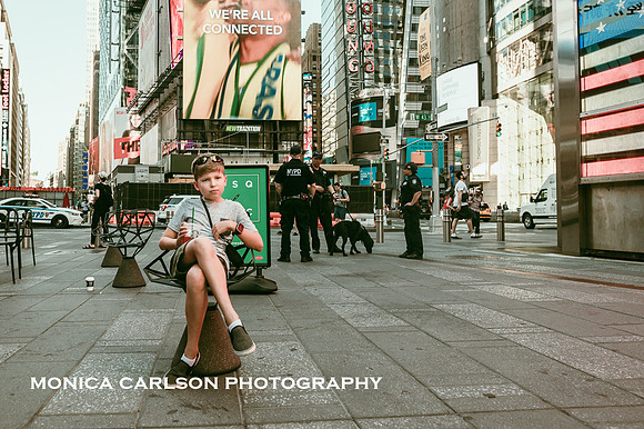 boy relaxing while drinking starbucks in times square while police stand in the distance behind him