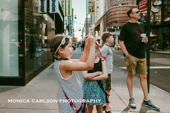 Little girl tourist takes a photo in Times square