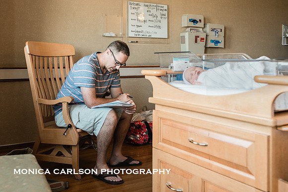 Father filling out paper work in a hospital room with his newborn baby sleeps in a bassinet