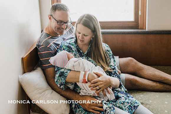 mother and father hold their freshly born baby in a hospital room by monica carlson