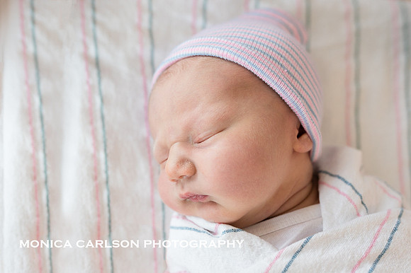 Freshly born baby boy in his hospital cap and blanket by monica carlson