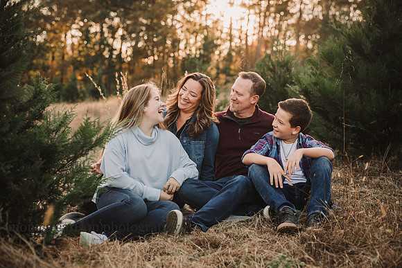 family of four laugh together at sunset while visiting hunter family farm