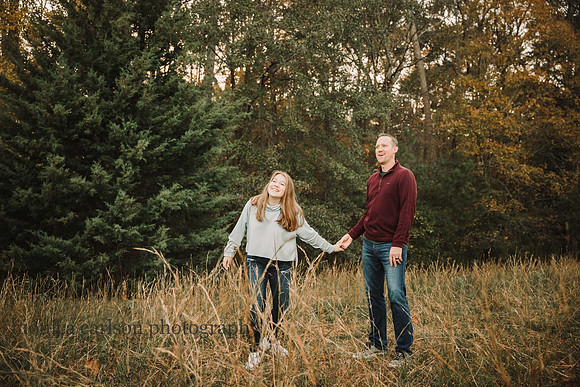 father and teen daughter share a funny moment whill walking along tall grass