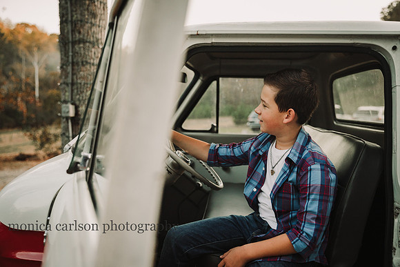 teen boy sits in a cab of a old truck