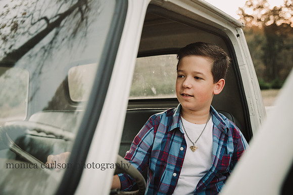 teen boy happily looks around the cab of a vintage truck during a mini session in milton, georgia