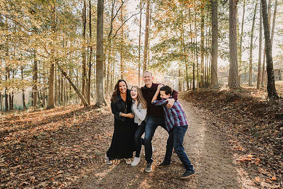 family of four playfully walk along a wooded path in milton, ga during a photo session