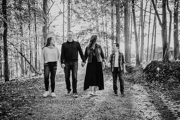 family of four walks togehter along a wooded path by monica carlson