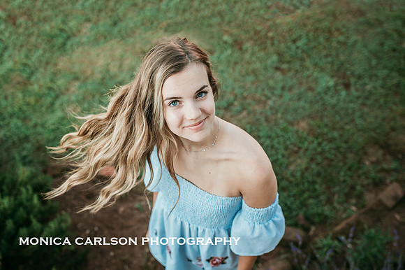 a teenage girl whose hair inn blowing in the wind with grass behind her in Roswell, GA