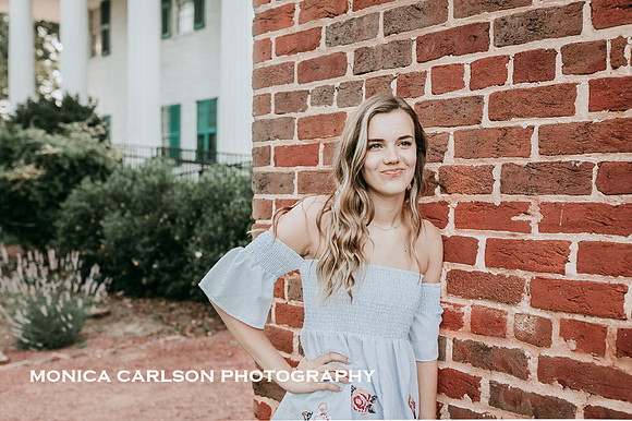 high school senior leaning against a brinck wall at Barrington hall.