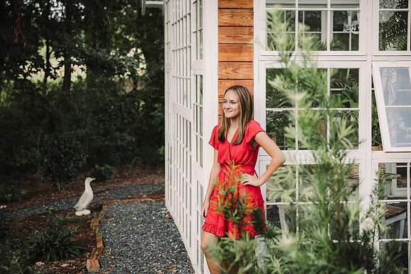 teen girl leans against a greenhouse in Lawrenceville