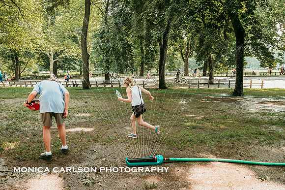 boy and girl running through a sprinkler in central park