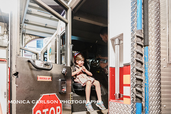 little girl sits buckled into a New york city fire truck