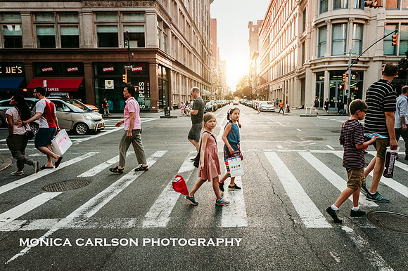 group of people cross a new york street at sunset