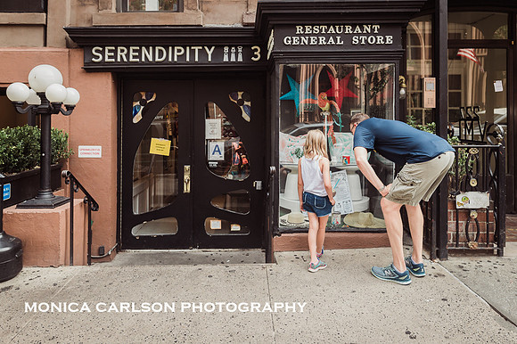 father looks in the window of Serendipity in New York CIty