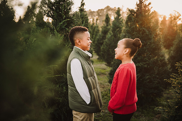 tween brother and sister looking at each other during a Christmas tree farm mini photo session