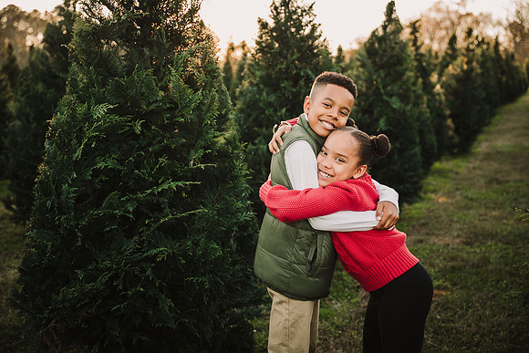 brother and sister hugging among christmas trees in Cumming, GA