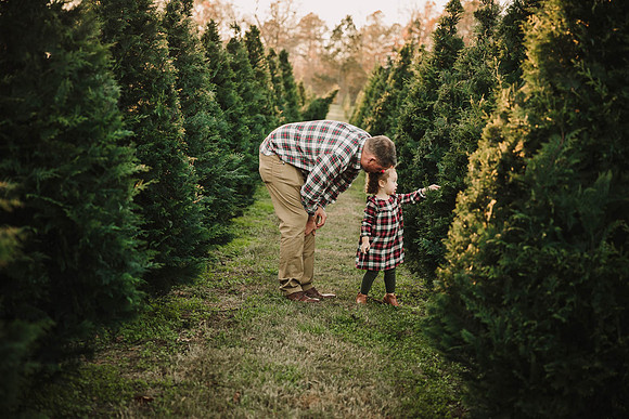 toddlers pointing to show her father something beyond the christmas trees