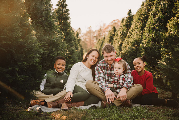family of fice sitting on a blanket at Bottoms Christmas Tree farm
