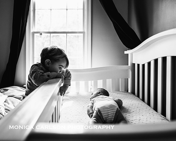 Big brother watching his new sibling laying in its crib in Marietta
