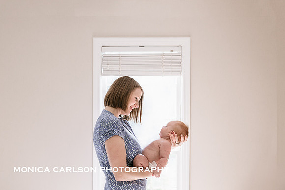 Mother holding her newborn baby boy in front a window at her home in Marietta