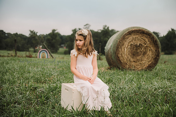 young girl sits on a antique box on a farm field in lawernceville, ga