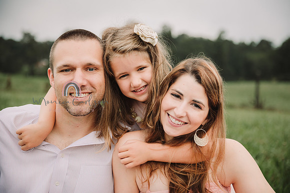 little girl snuggles her parents from behind by monica carlson